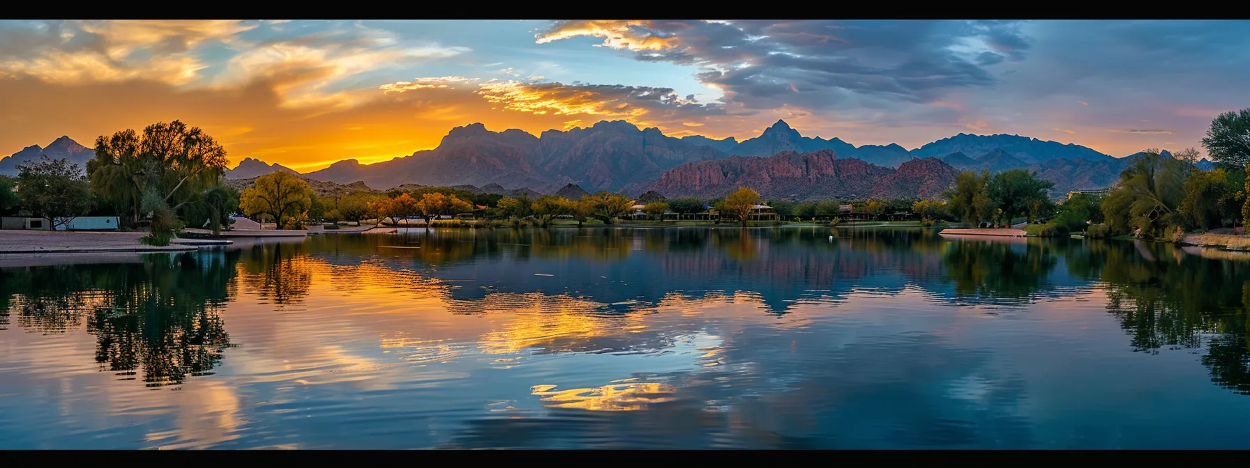 a breathtaking sunset bathes a tranquil lake in golden hues, while majestic mountains rise dramatically in the background, reflecting the vibrant colors on the water's surface.