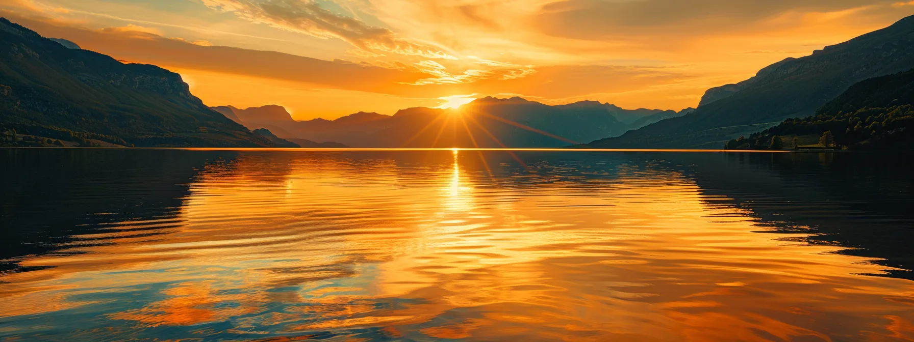 a vibrant sunset casts a warm golden hue over a serene lake, with silhouetted mountains reflecting beautifully in the still water.