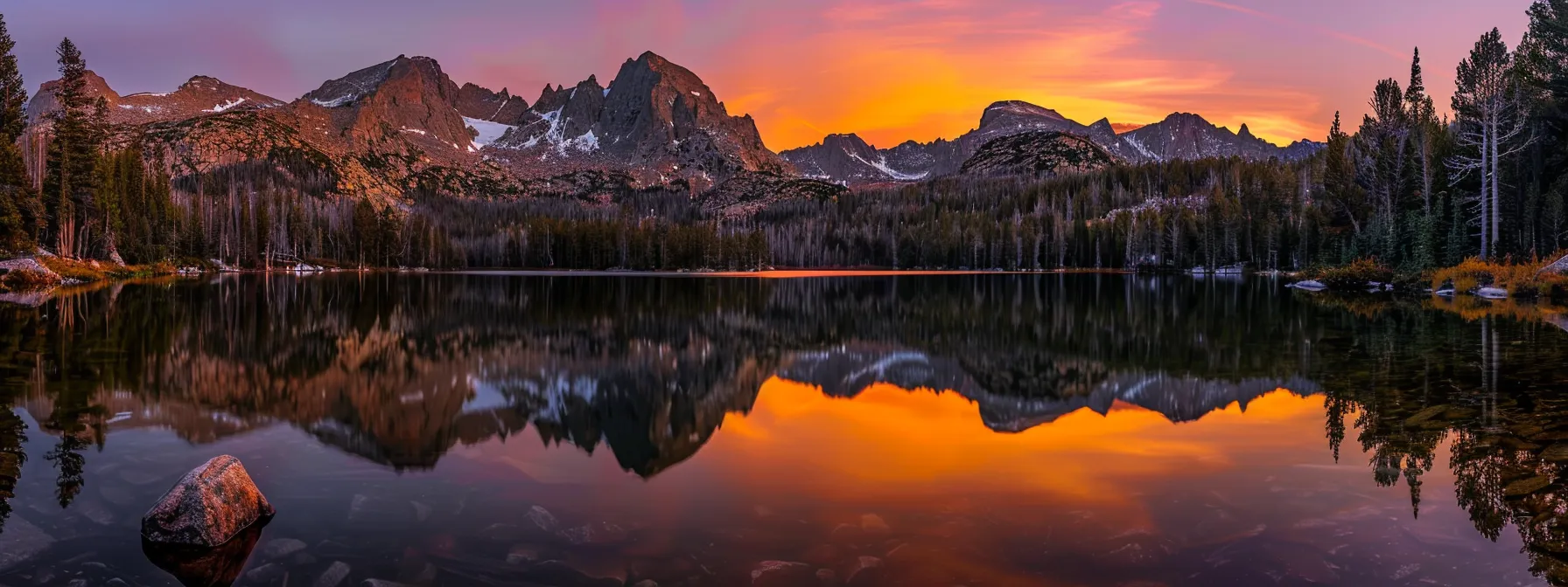 a vibrant sunset casts golden hues over a serene lake, reflecting the majestic silhouettes of distant mountains under a sky streaked with brilliant oranges and purples.
